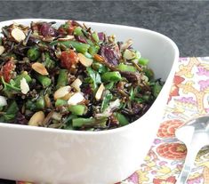 a white bowl filled with salad on top of a colorful napkin next to a fork