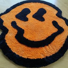 a smiley face rug on the floor with black and orange trim around it's edges