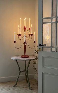 a small table with many candles on it in front of a door and a window