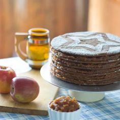 a stack of pancakes sitting on top of a wooden cutting board next to an apple