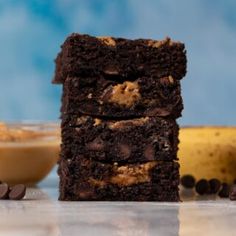 three brownies stacked on top of each other with chocolate chips and bananas in the background