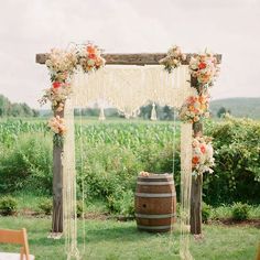 an outdoor wedding ceremony setup with flowers on the arch and wooden barrels in the foreground