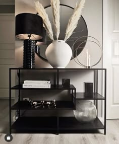 a black shelf with some vases and other items on it in front of a mirror