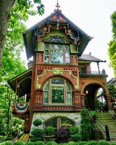 a very pretty house that is in the middle of some bushes and trees with lots of windows