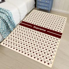 an area rug with the name supreme on it in front of a bed and nightstand