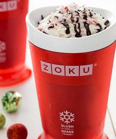 two red cups filled with ice cream and candy canes on top of a white table