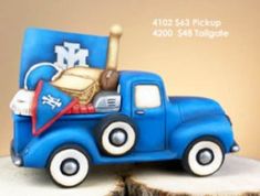 a blue truck with a basket and baseball bat in the bed is on top of a tree stump