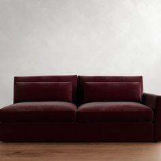 a red couch sitting on top of a hard wood floor next to a white wall