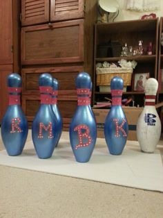 three blue bowling pins with letters painted on them