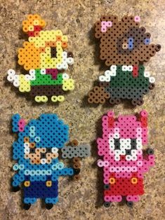 three perler beads are sitting on a counter top, one has an animal and the other has a bear