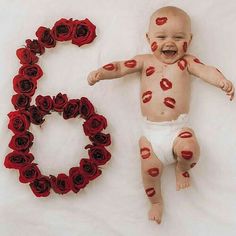 a baby laying next to the number 50 with roses on it's face and body