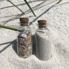 two glass bottles filled with sand and sea shells