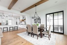 a dining room table and chairs in front of an open kitchen