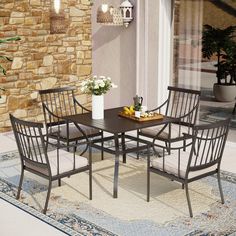 an outdoor dining table with four chairs and a potted plant on the side of it