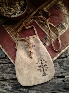 an old purse sitting on top of a wooden table next to a bowl of buttons