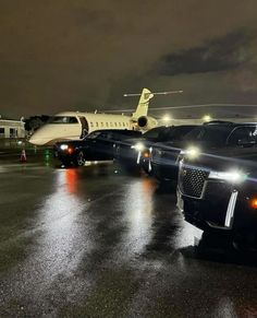 a row of cars parked in front of an airplane on the tarmac at night