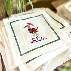 four embroidered napkins on top of each other with the words holiday holidays written on them