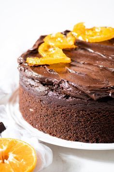 a chocolate cake topped with orange slices on top of a white plate next to an orange slice