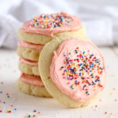 three cookies with pink frosting and sprinkles are stacked on top of each other