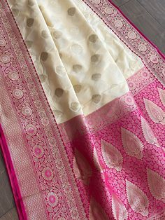 Gorgeous handloom soft banarasi silk saree in off white. Dull gold silk thread motifs are woven all over the saree. Magenta border and anchal is intricately woven with zari as well. Comes with a contrast magenta blouse piece. This saree is perfect for festival and formal occasions. Saree is 6+ yards long 45 inches wide Blouse piece is 37 inches Care: Dry clean only Disclaimer: Color and shade of saree may vary in the pictures than the actual item. There might be slight weaving irregularities since the product is woven by hand. White Art Silk Dupatta With Zari Weaving, Off White Tussar Silk Dupatta For Diwali, White Katan Silk Dupatta With Zari Weaving, Cream Katan Silk Traditional Wear With Zari Weaving, White Tussar Silk Saree With Zari Weaving, White Silk Saree With Zari Weaving, Cream Tussar Silk Dupatta For Diwali, Cream Katan Silk Traditional Wear For Festivals, White Traditional Wear With Zari Weaving For Ceremonies