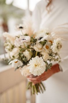 a woman holding a bouquet of white flowers