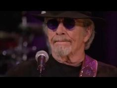 an older man wearing sunglasses and a hat is singing into a microphone