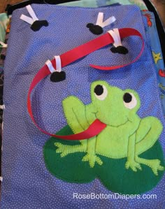 a green frog is sitting on top of a blue bag