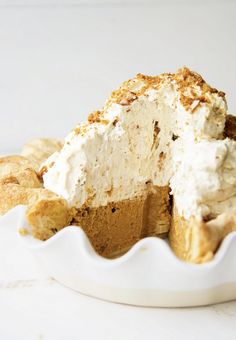 a piece of pie with whipped cream on top in a white dish next to some cookies