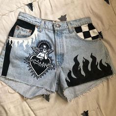 a pair of jean shorts with flames painted on the side and an image of a woman