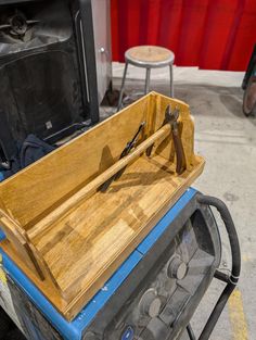 an old wooden tool box sitting on top of a blue cart with tools in it