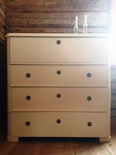 a white dresser with six drawers and two bottles sitting on it's top shelf