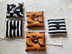 four halloween pillows with black and white designs on them, one has a button in the middle