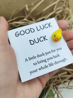 a hand holding a card with a rubber ducky on it's back and the words good luck in front of it