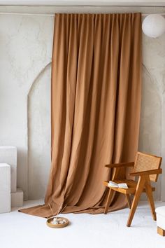 a chair sitting in front of a brown curtain