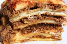 several pieces of lasagna stacked on top of each other with cheese and meat