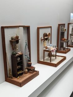 three miniature mirrors on top of a white shelf next to each other with various items in them