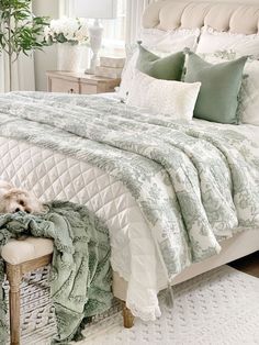 a white bed with green and white comforters