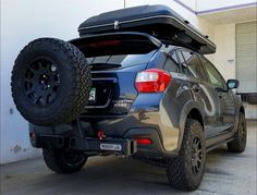 the back end of a vehicle with an suv on it's flatbed and large tires