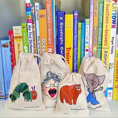 three little bags filled with books sitting on top of a book shelf next to a bunch of books