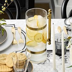 a table topped with plates and glasses filled with lemon slices next to crackers and cookies