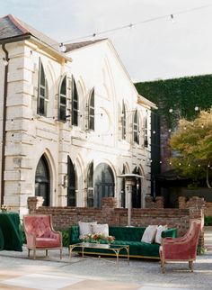 a living room with green velvet couches in front of a large white building