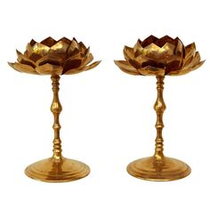 two gold colored candlesticks sitting on top of each other in front of a white background