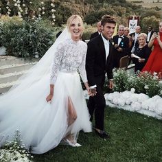 a bride and groom walking down the aisle at their outdoor wedding ceremony with guests in the background