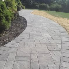 a paved walkway with grass and bushes in the background