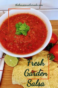 a bowl of fresh garden salsa next to tortilla chips and lime wedges