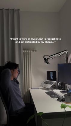 a man sitting in front of a computer on top of a desk next to a window