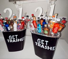 two buckets filled with alcohol bottles sitting on top of a white counter next to each other