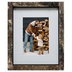 a man and child standing in front of stacks of firewood with their hands on each other