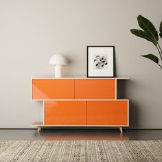 an orange cabinet in the corner of a room with a lamp on it and a plant next to it