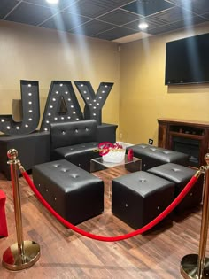 a room with black leather couches and red ropes on the floor next to it